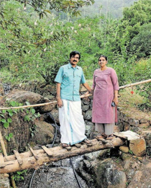 Vinod and Jisha standing on a small waterfall flowing through Dream Acres farm in Kerala